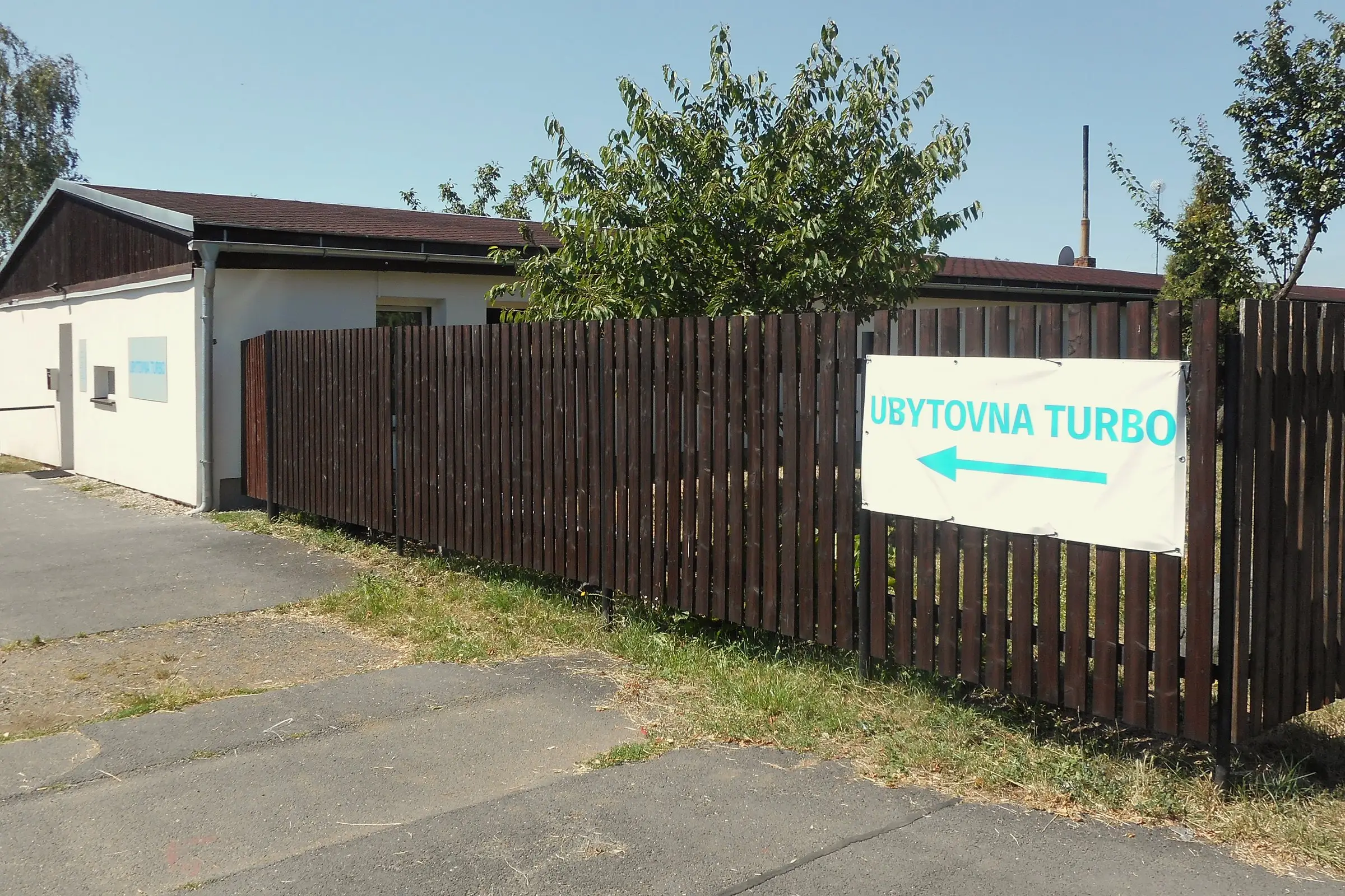 Budova Ubytovny TURBO s cedulí na plotě, ulice Kosmonautů v Chomutově